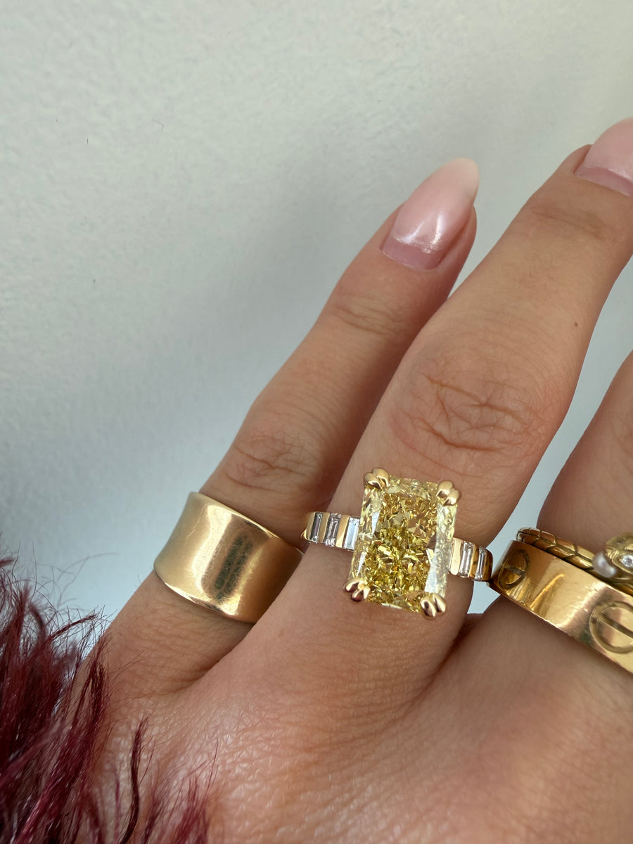 A yellow diamond ring worn with two wide gold bands