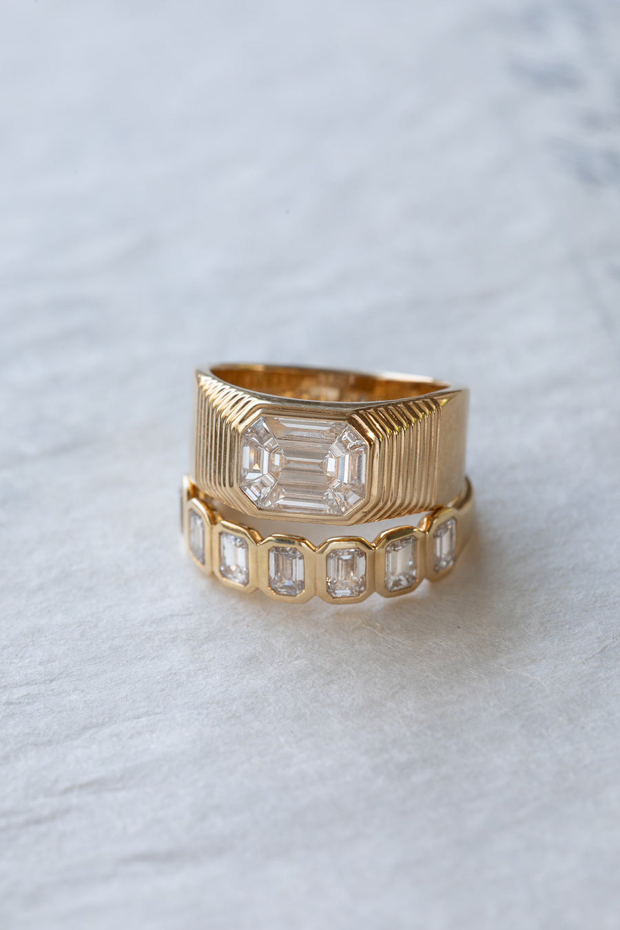 A fluted gold emerald-cut ring stacked with a diamond band, from The Lane editorial.