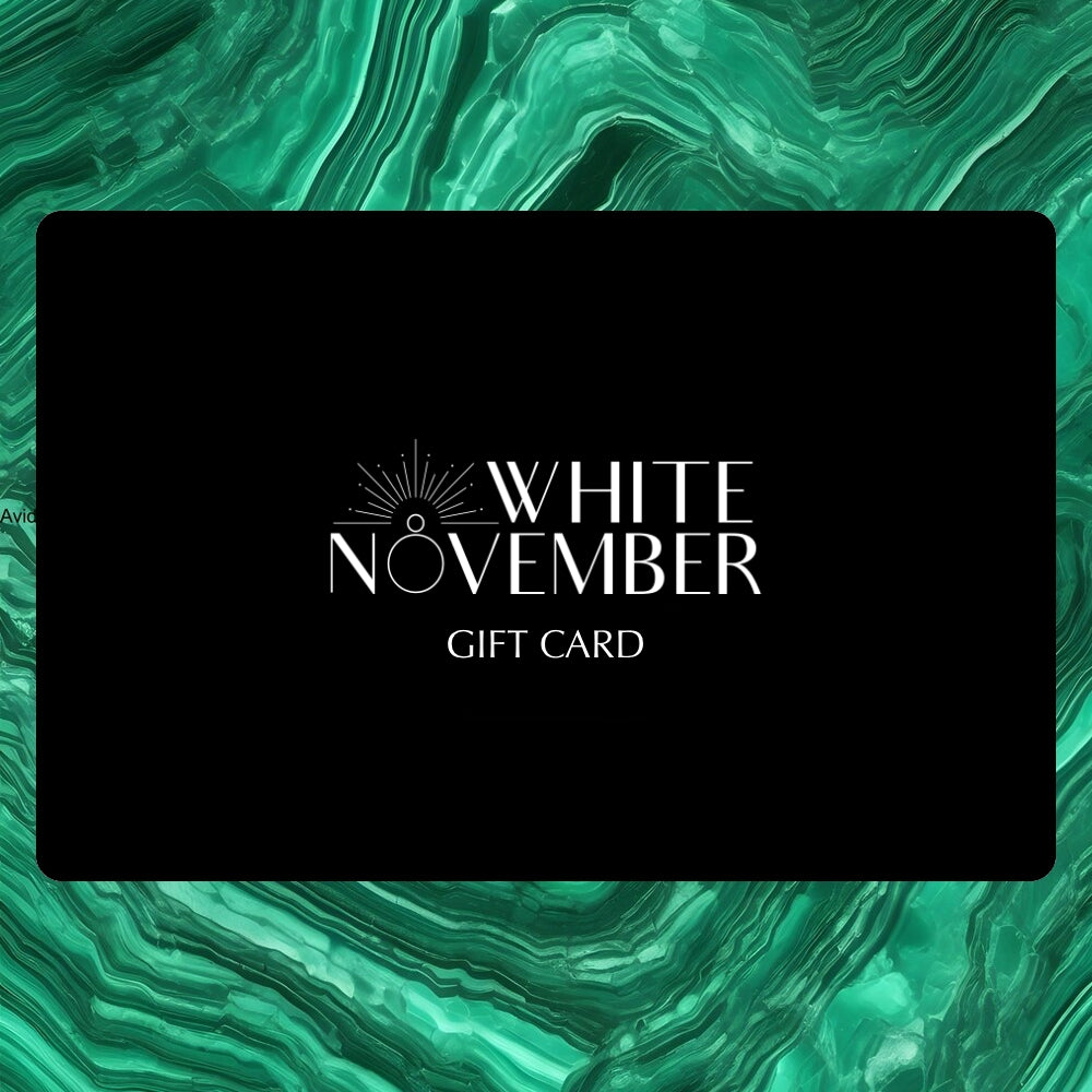 The White November gift card, black with the wordmark, on malachite.